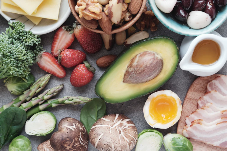 A photo of various keto-friendly foots on a table, including avocado, berries and meat.