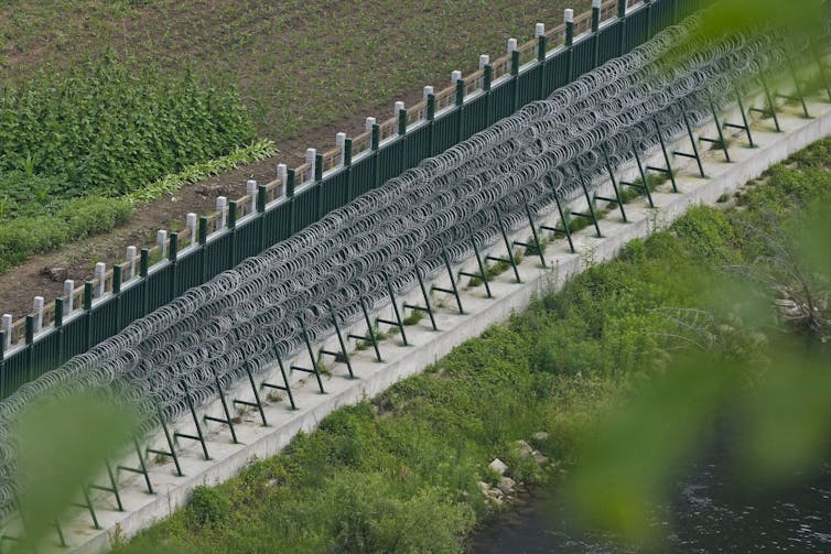 A multi-layer wire and concrete border fence.