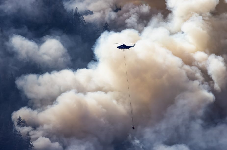 Wildfire Service helicopter flying over British Columbia forest fire.