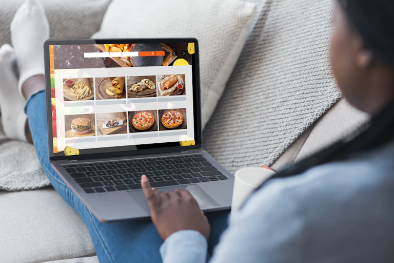 girl sits on couch and looks at junk food ads on screen