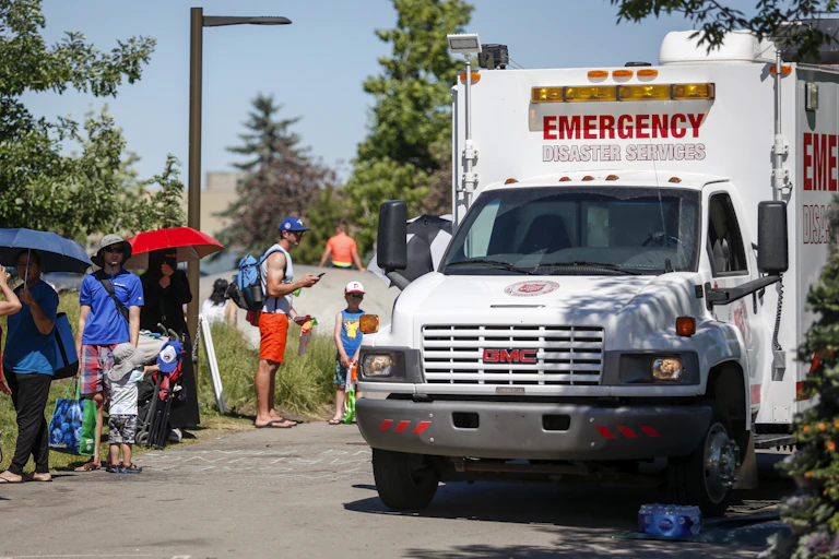 People queue next to emergency service truck in heatwave