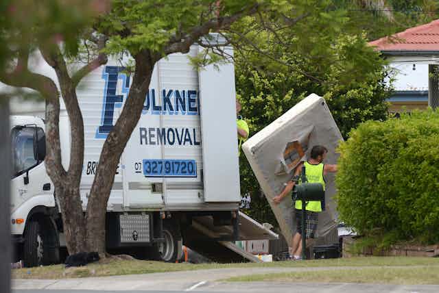 A man carries a mattress from a removal truck