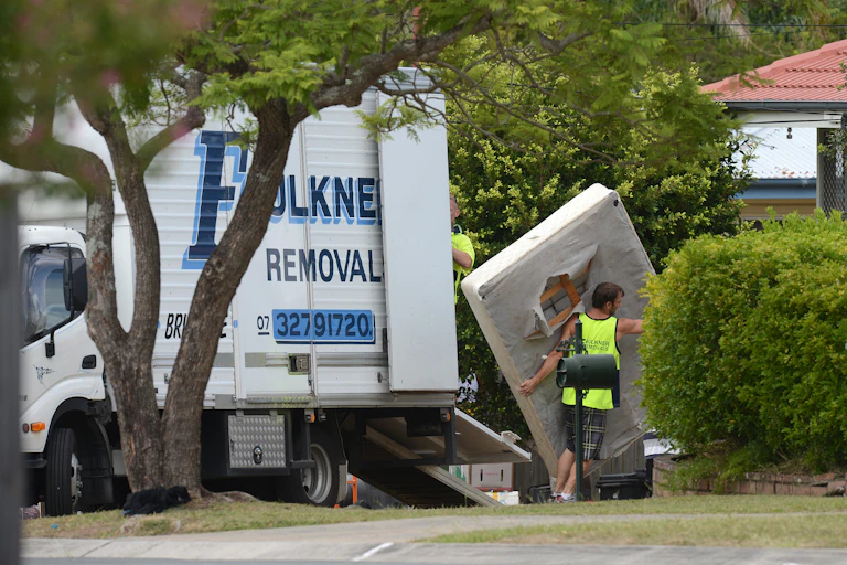 A man carries a mattress from a removal truck