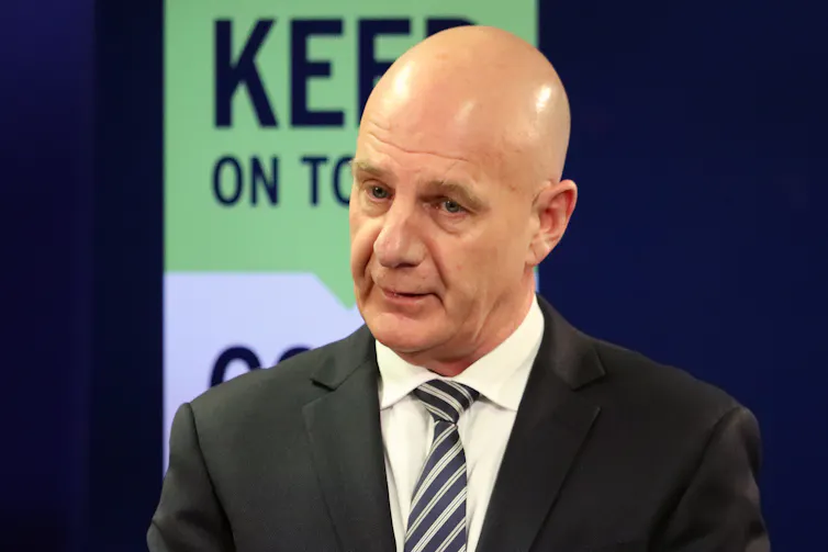 Man in suit and tie speaking at a press conference