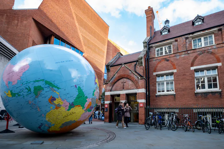 A sculpture of a globe in front of a brick building.