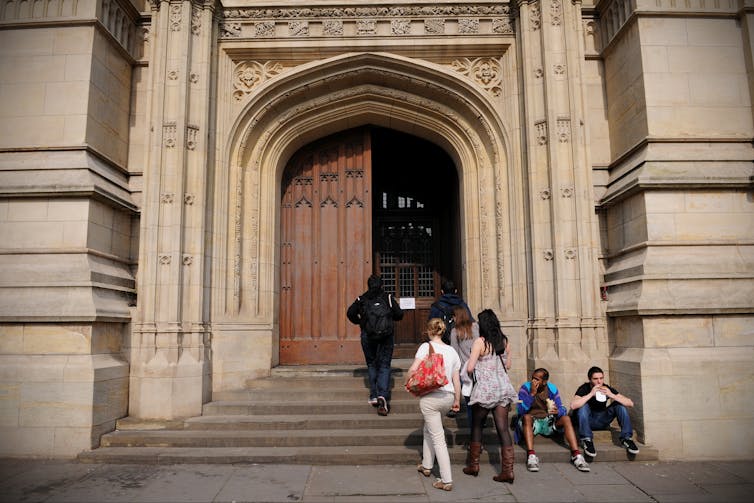 Students walk into a large university building.