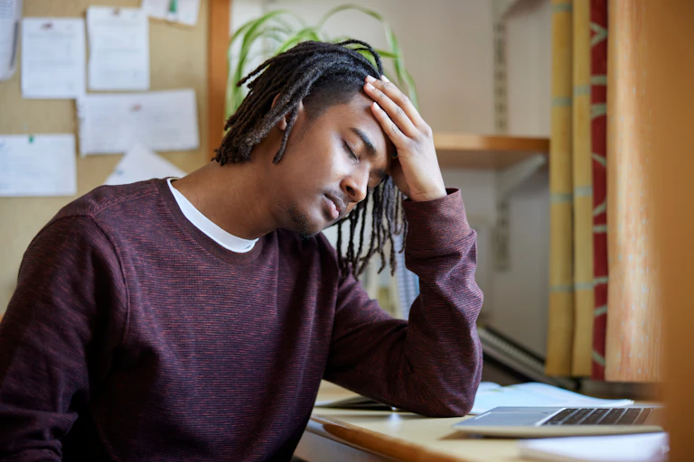 A man holds his head and closes his eyes.