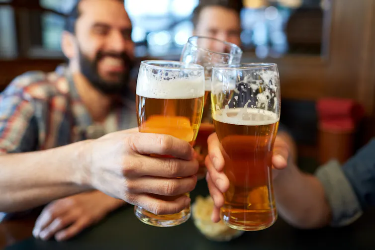 A group of men cheers their pints of beer.