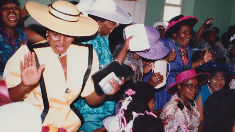 A group of women smartly dressed and singing in church.