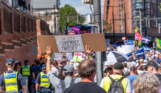 Melbourne, Victoria, Australia, January 15, 2022: A protestor is holding a Conspiracy Theory sign as a symbol of protest during an anti vaccination march through the city.