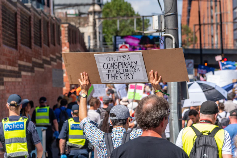 Melbourne, Victoria, Australia, January 15, 2022: A protestor is holding a Conspiracy Theory sign as a symbol of protest during an anti vaccination march through the city.