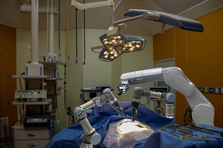 An operating room with no people and only several robot arms hovering above a patient