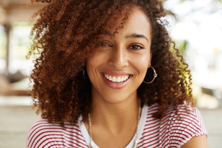 Woman outside with striped top smiles at camera