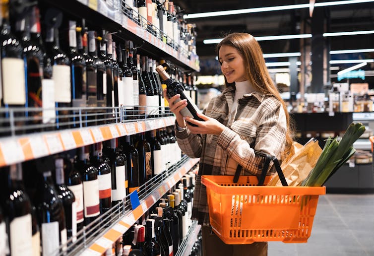 Woman selecting wine in supermarket