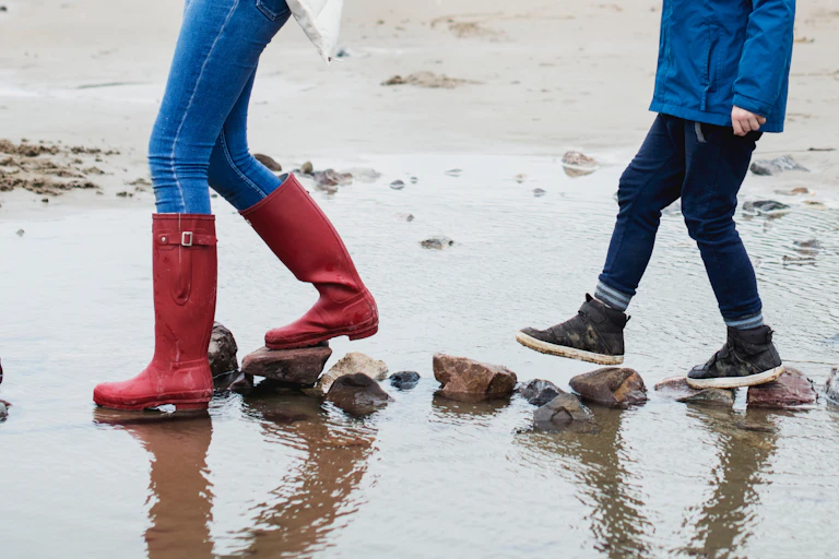 Children walking across stones on a beach.