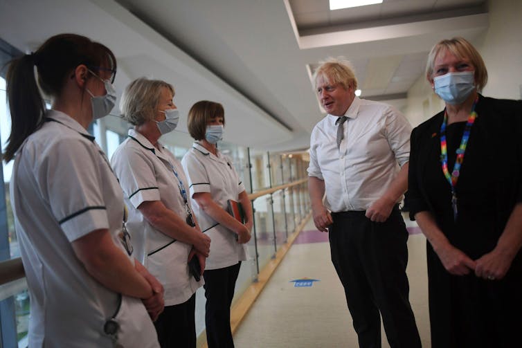 Boris Johnson talks to three masked nurses in a hospital corridor