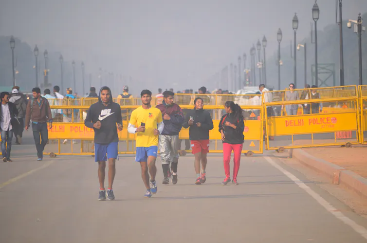 Groupes d’hommes courant dans le smog à Delhi