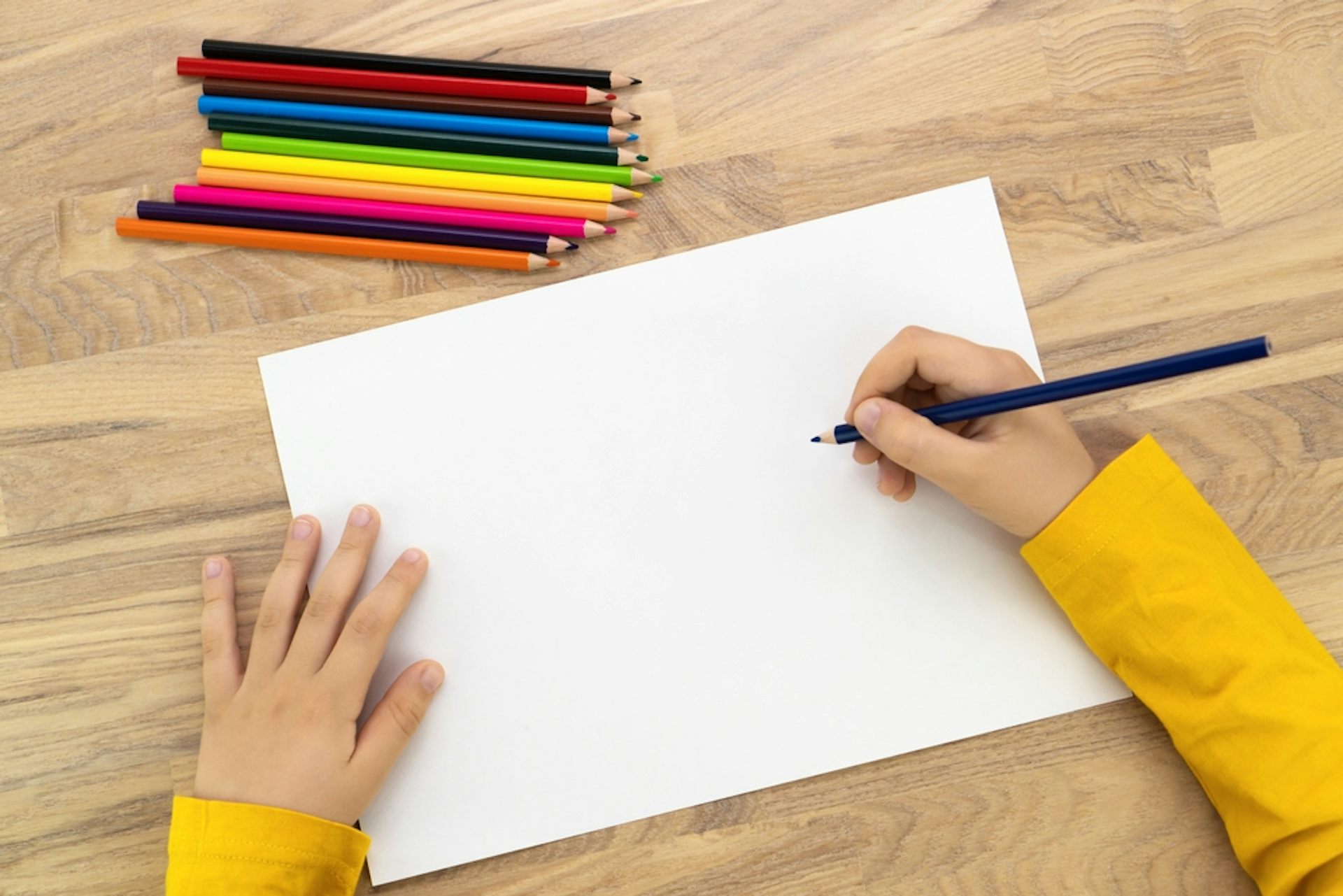 Un enfant se prépare à dessiner sur une feuille blanche