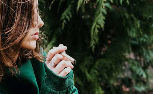 Photo d’une adolescente avec un joint de cannabis à la main.