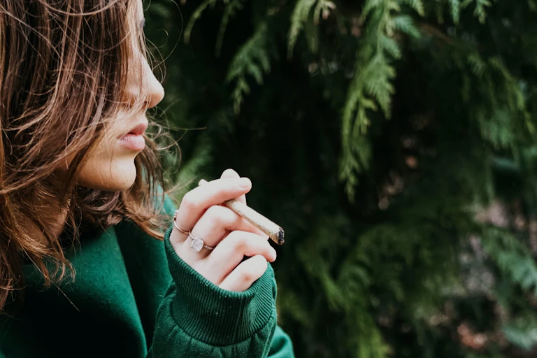 Photo d’une adolescente avec un joint de cannabis à la main.