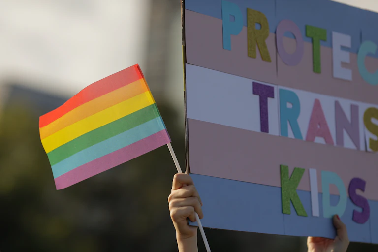 A Pride flag and Protect Trans Kids sign
