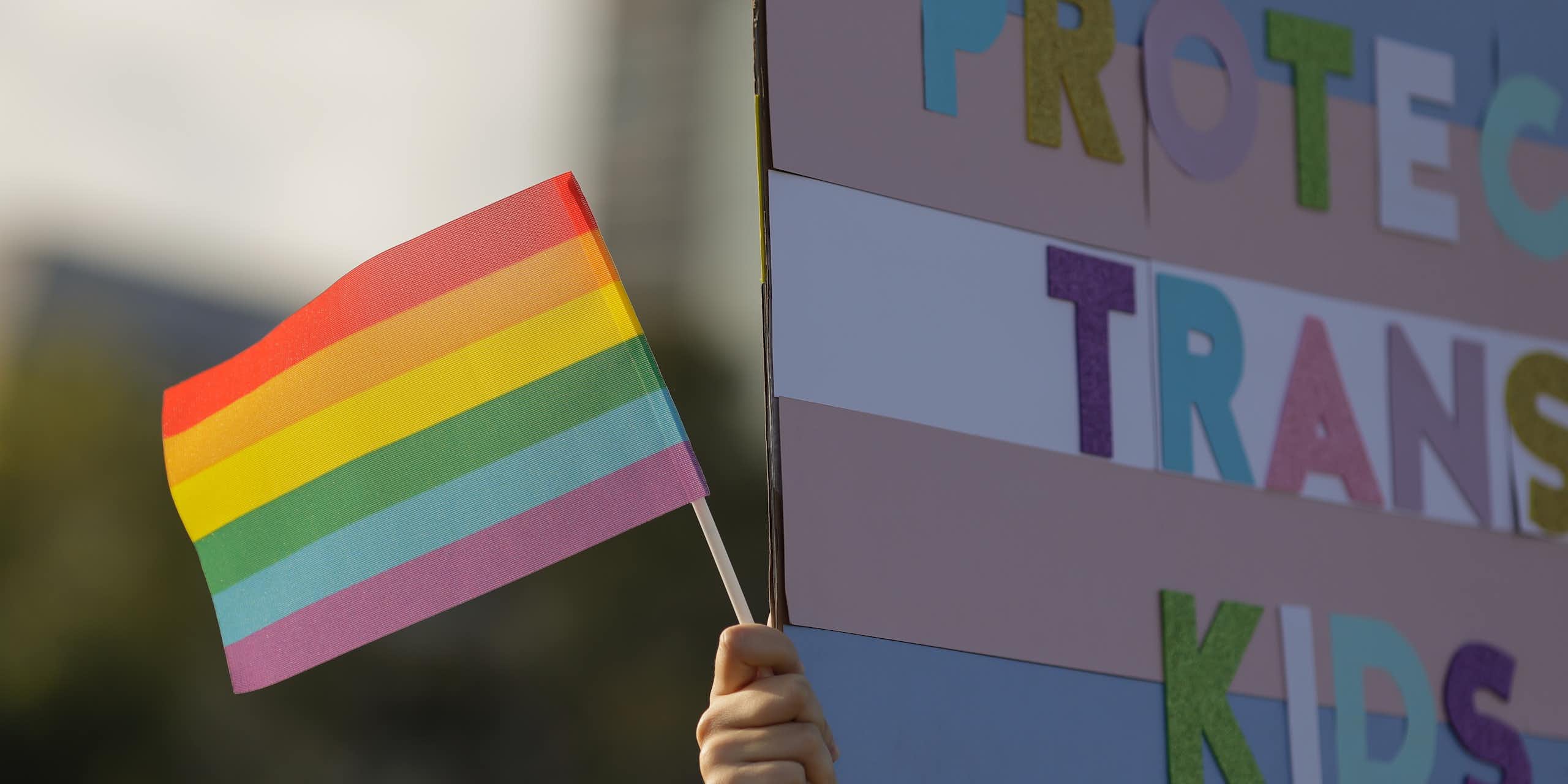 A Pride flag and Protect Trans Kids sign