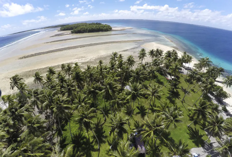 Aerial view of Marshall Islands atoll where a section of treed land has been washed away