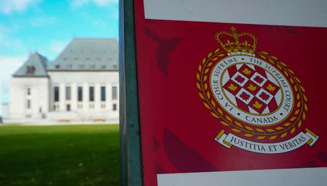 The Supreme Court is seen behind a red and white banner that says Supreme Court of Canada.