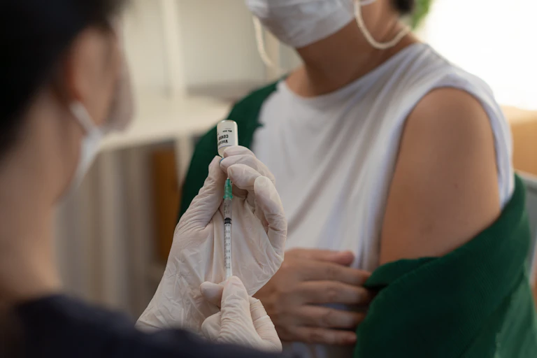 health worker holds syringe as patient exposes upper arm