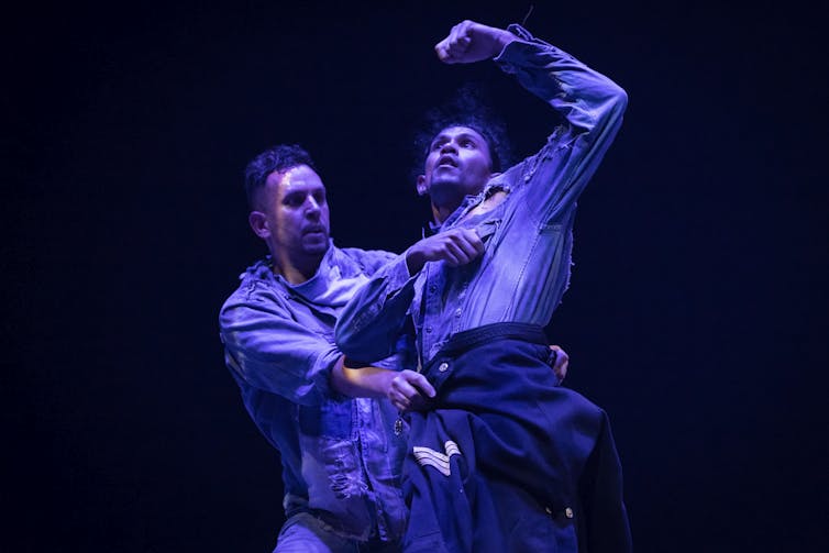 Two dancers in blue light and denim clothes.