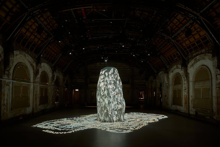 A sculpture with projected flowers in a dark ballroom.