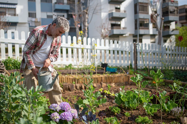 Man waters flowers in garden