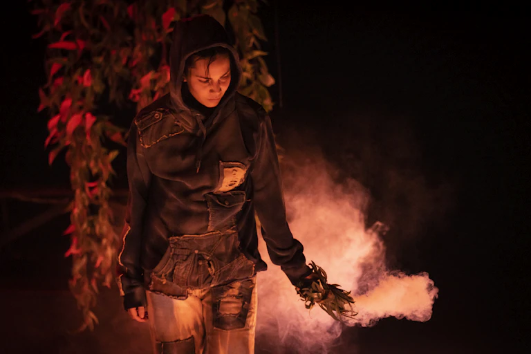 A woman in red light performing a smoking ceremony.