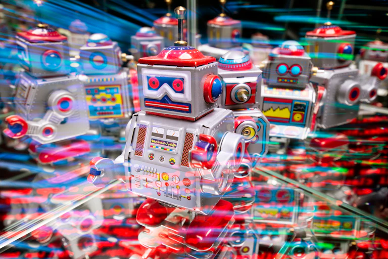 A robot full of lights and colors stands among other robots.