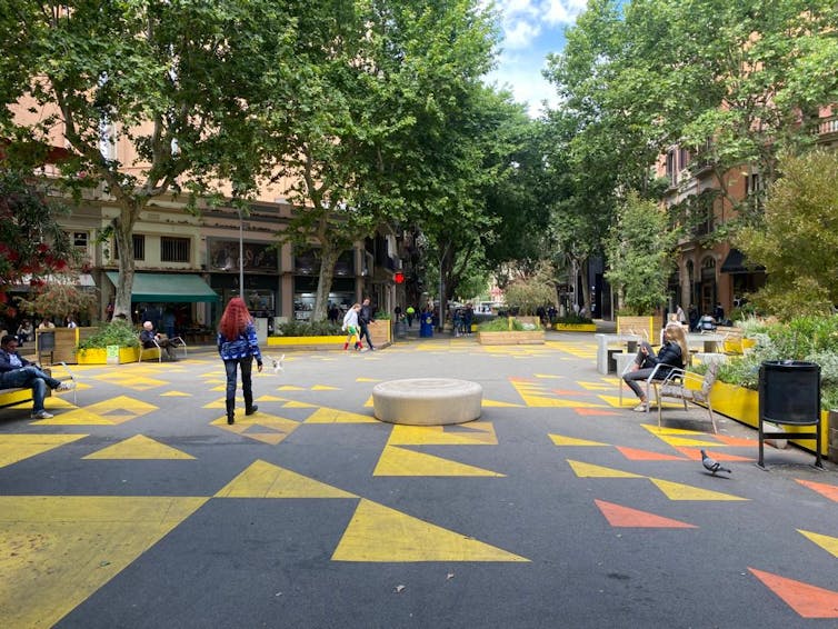 Um bairro de baixo tráfego com assentos na calçada e decoração colorida.