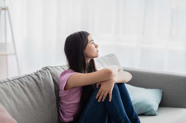 A teenage girl sitting on a couch.