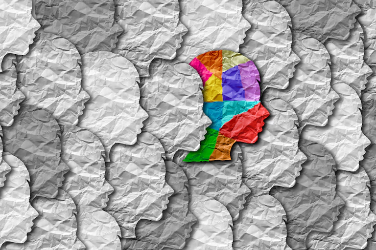 A digital image depicting a colourful head among other grey and white heads.