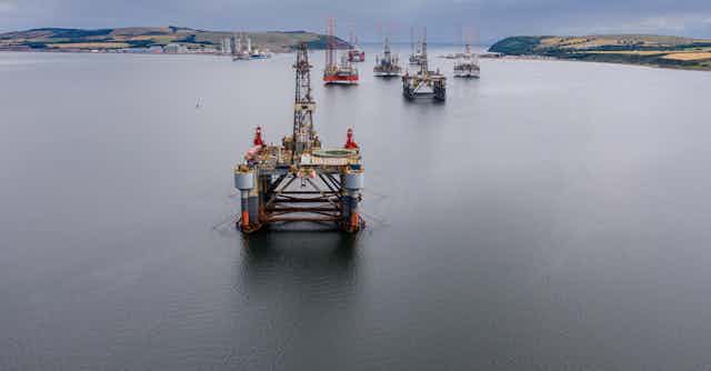 A fleet of discarded oil rigs in the water.