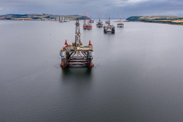 A fleet of discarded oil rigs in the water.