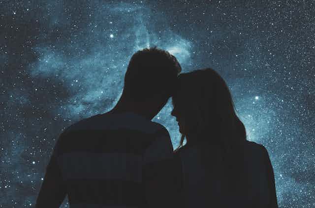 Silhouettes of a young couple under a starry sky