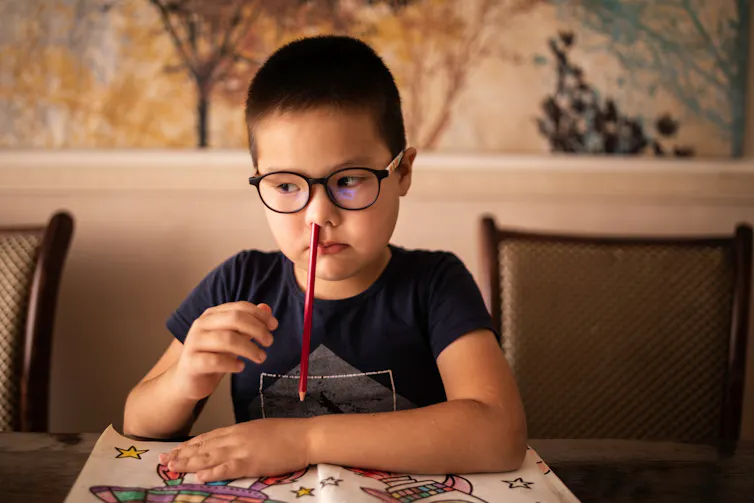 Bored child with pencil up his nose.