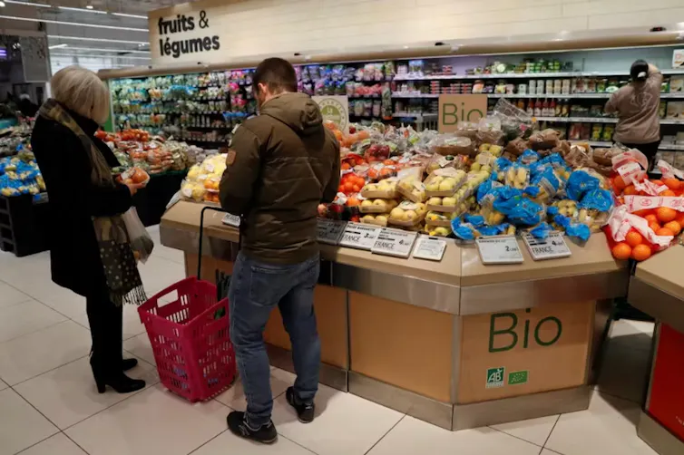 personnes devant un étalage bio dans un supermarché