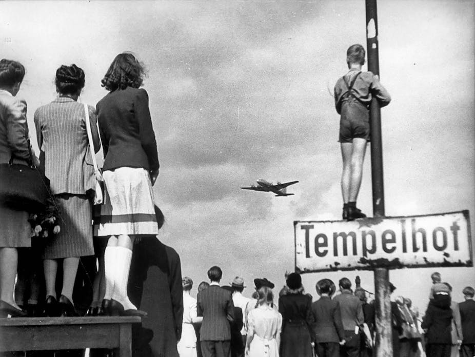 People looking at a plane arriving with supplies at Berlin Templehof airport.