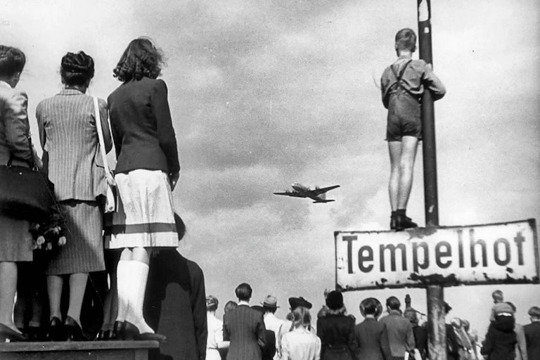 People looking at a plane arriving with supplies at Berlin Templehof airport.