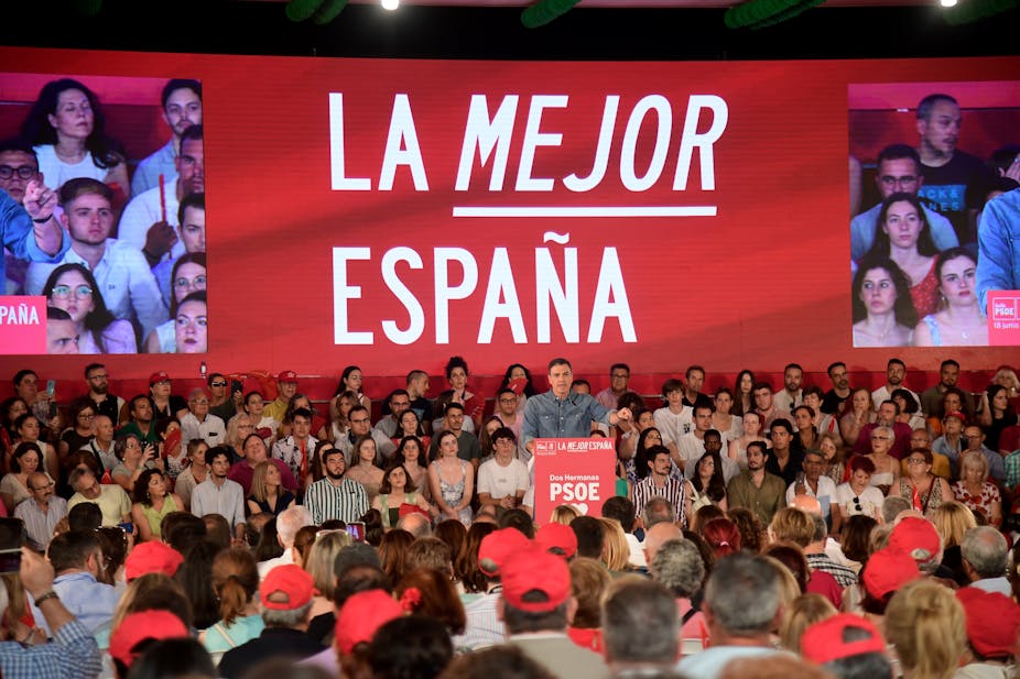 Pedro Sanchez au pupitre devant une salle pleine, devant une pancarte portant le slogan « La mejor España »