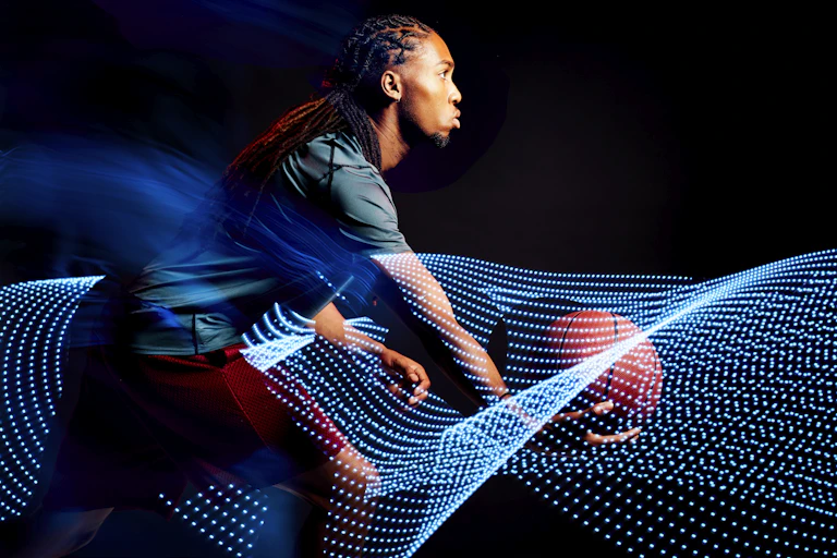 A young man with a basketball moves amid images of computer-generated motion waves.