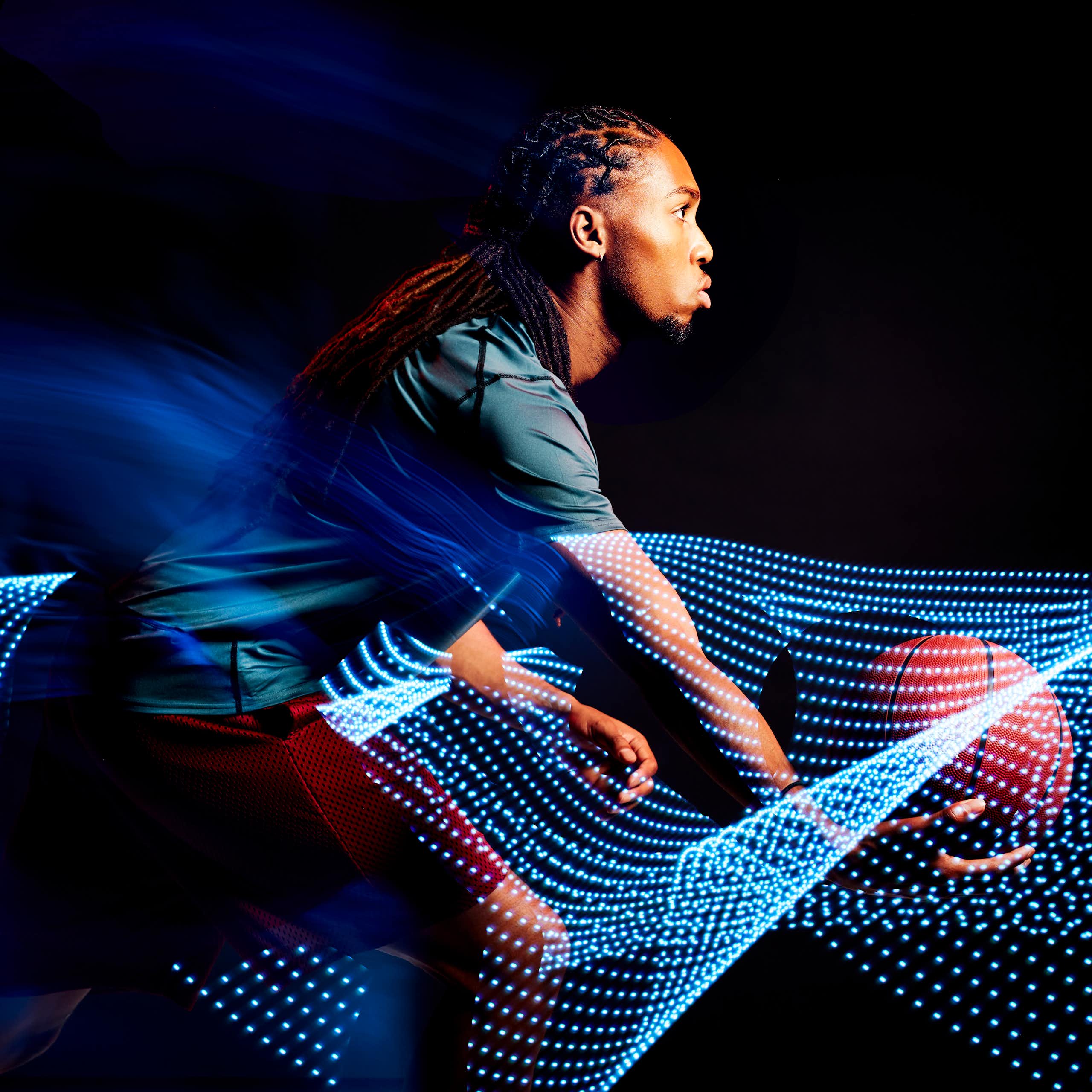 A young man with a basketball moves amid images of computer-generated motion waves.