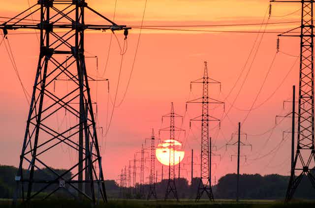 Electricity pylons with setting Sun in background
