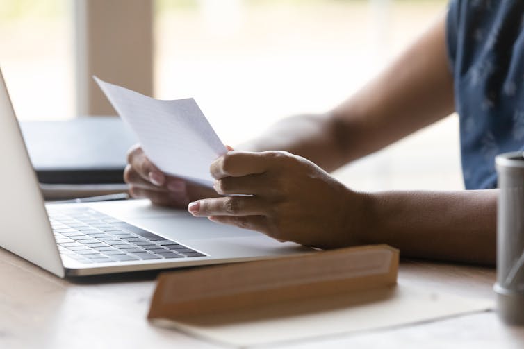 A woman sits at her desk, reading a letter.