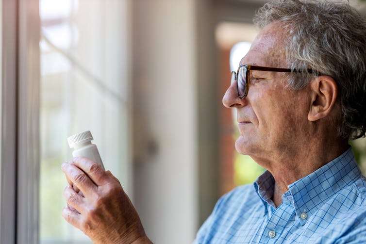 Older man looks at vitamin bottle